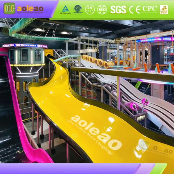 Commercial indoor slide park equipment featuring a giant yellow curved slide and elevated play platforms